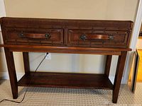 Front view of console table showing wicker drawers, leather pulls, lower shelf and legs
