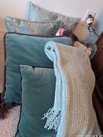Stack of teal cushions and folded light blue throw