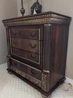Front view showing four drawers, carved gold scroll accents, bail pulls