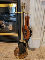Full view of brass stand with hanging shovel, poker, broom and separate bellows