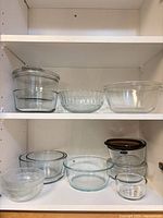 Cabinet view showing all glass bowls and storage pieces on two shelves