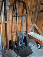 full view of hand truck against wall showing frame, wheels, folding base