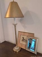 Full view of gold-tone lamp with shade, framed duck print and beveled mirror