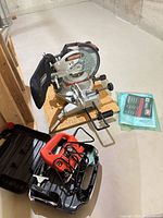 Group view of miter saw, jig saw with case, manual