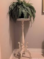 Full view of wood pedestal plant stand with faux fern on top