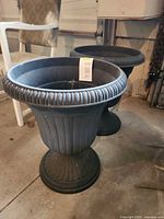 Two matching dark grey plastic urn planters side by side