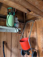 Spreader and two pump sprayers hanging on wall shelf