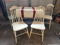 White drop-leaf table with four chairs arranged around it