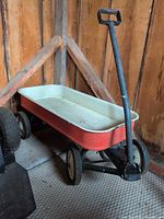 Full view of red metal wagon in corner