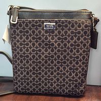 Front view of Coach patterned crossbody showing silver-tone hardware and hangtag