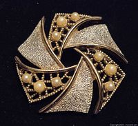 Front view of Emmons pinwheel brooch showing gold-tone finish, openwork and faux pearls