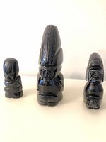 Front view of three black obsidian figurines in size order