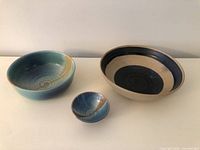 Three bowls grouped on tabletop showing relative sizes and glaze patterns