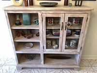 Front view of solid wood whitewashed sideboard showing glass doors and shelves