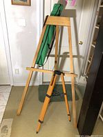 Full view of wooden easel and tripod with green bag