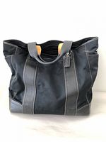 Front view of black Coach tote showing canvas body and leather trim