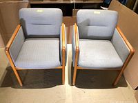 Front view of both oak armchairs with grey fabric upholstery