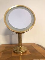 Front view of brass-tone lighted mirror, light off