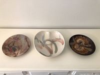 Three signed studio pottery plates on surface