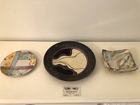 Three studio pottery plates displayed side by side