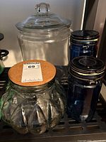 Group view of four jars: fluted clear jar with cork lid, large clear jar with glass lid, two blue jars with black lids
