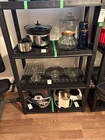 Full view showing entire black plastic shelving unit with contents on shelves