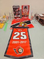 Full lot view showing two boxed bobbleheads, two glass mugs, towel, hanging pennant