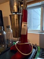 Side view of Waring red drink mixer with stainless cup inserted
