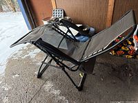 Full view of gray/black zero gravity recliner, folded open, showing mesh seat and bungee lacing