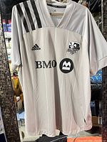 Front view of jersey showing crest, sponsor, Adidas logo