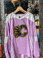 Front view of purple Calgary Flames Adidas jersey on hanger
