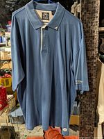 Full view of blue Ahead Authentics polo shirt on hanger