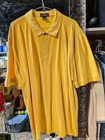Full view of yellow Antigua polo shirt on hanger