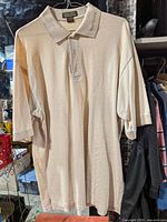 Full front view of beige Ash City polo shirt hanging