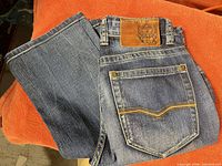 Front and back view of folded blue jeans showing color and rear pocket stitch