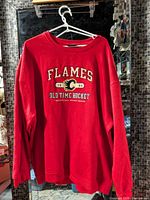 Full view of red Calgary Flames long sleeve shirt on hanger