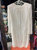 Full front view of beaded white dress on hanger