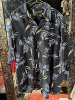 Front view of Cotton Reel palm leaf shirt on hanger