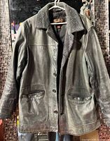 Full view of Danier leather jacket hanging, showing front, collar, pockets and overall wear