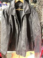 Full view of black leather jacket on hanger