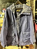 Front view of blue Eddie Bauer coat on hanger showing hood, pockets, closure