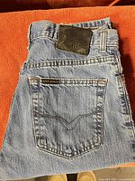 Full view of folded jeans showing back pocket and leather brand patch