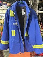 Front view of blue work jacket hanging, showing reflective stripes, zipper and pockets