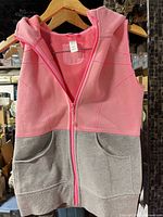 Front view of pink and grey Ivivva hooded vest hanging on hanger