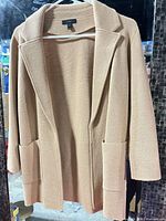 Full view of beige cardigan on hanger