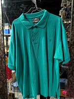 Full front view of teal polo shirt on hanger