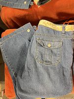 Full view folded denim capris showing rear pocket and belt loops