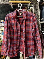 Front view of red and navy plaid flannel shirt on hanger