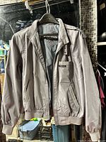 Front view of grey Members Only jacket on hanger showing overall style, zipper, pockets, cuffs and waistband