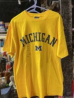 Front view of yellow Michigan T-shirt hanging on hanger